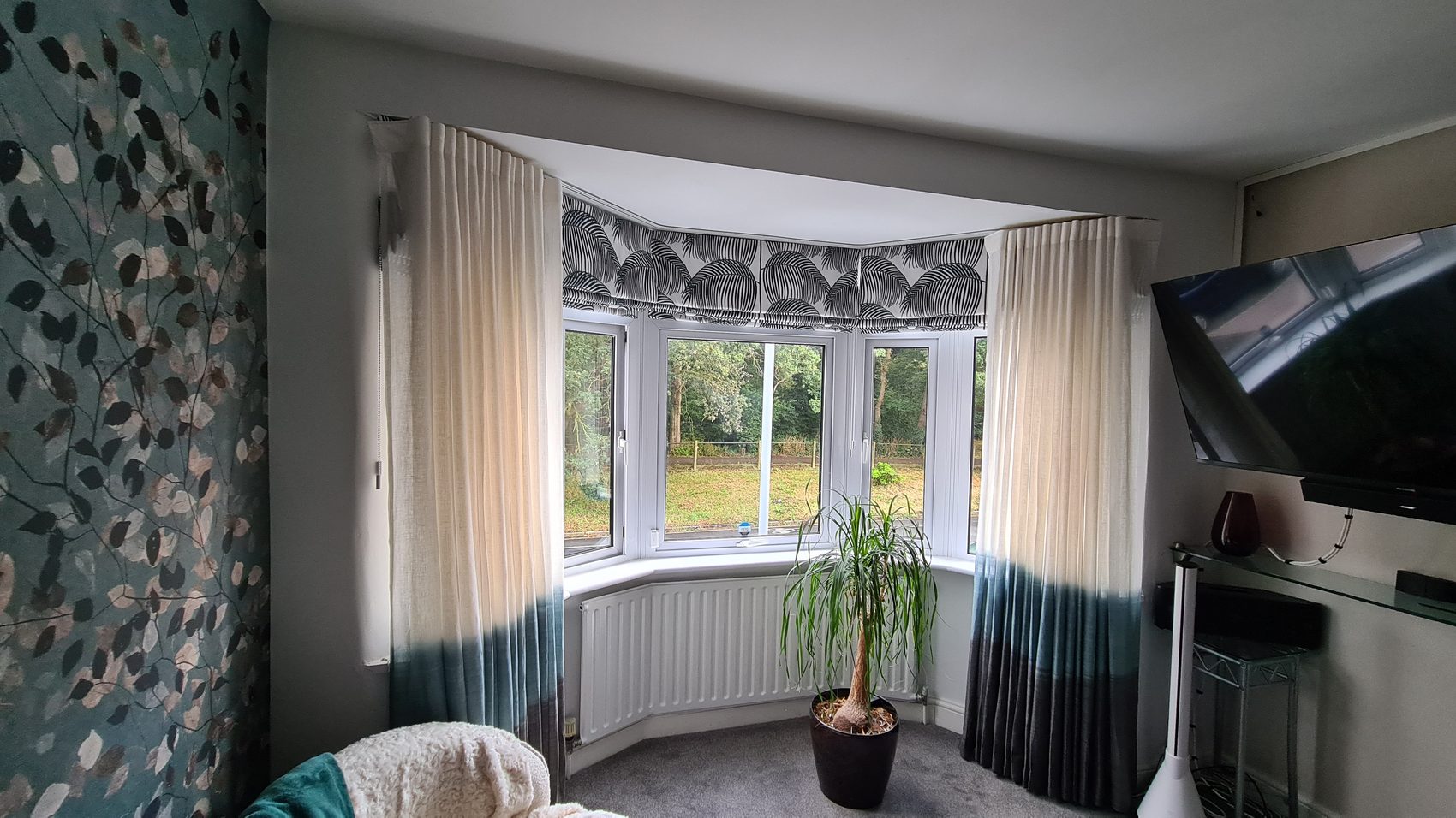 A bay with blinds inside the reveals and a patterned pair either side — the layered approach, where the blind handles daylight and privacy and the curtains do the softening. Very few rooms want all one or all the other.