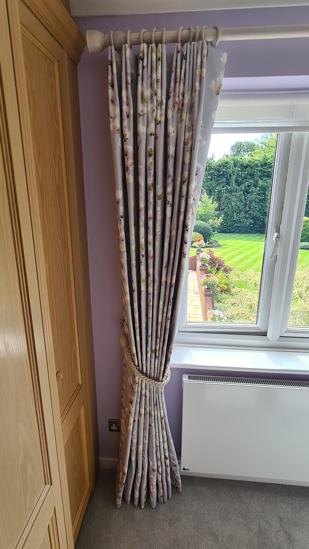 A single full-length drop in a soft woven stripe, tied back to clear the window entirely. Not every window wants a pair; where the wall is tight on one side, one well-hung curtain looks considered rather than compromised.
