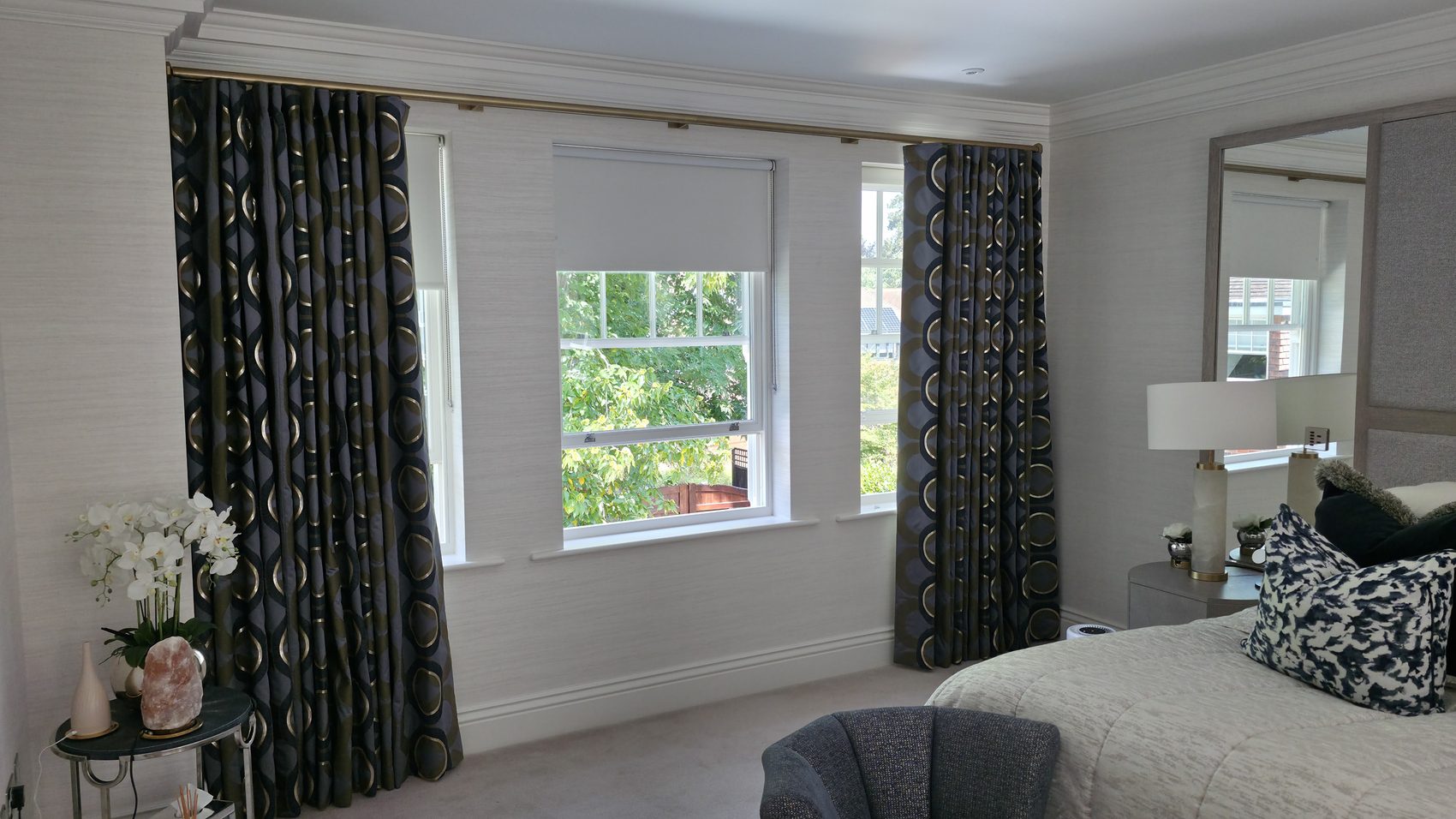 A large-scale patterned weave made up as a full-length pair on a slim pole set high and wide of the window, so the glass is left clear when the curtains are open and the wall reads taller than it is.